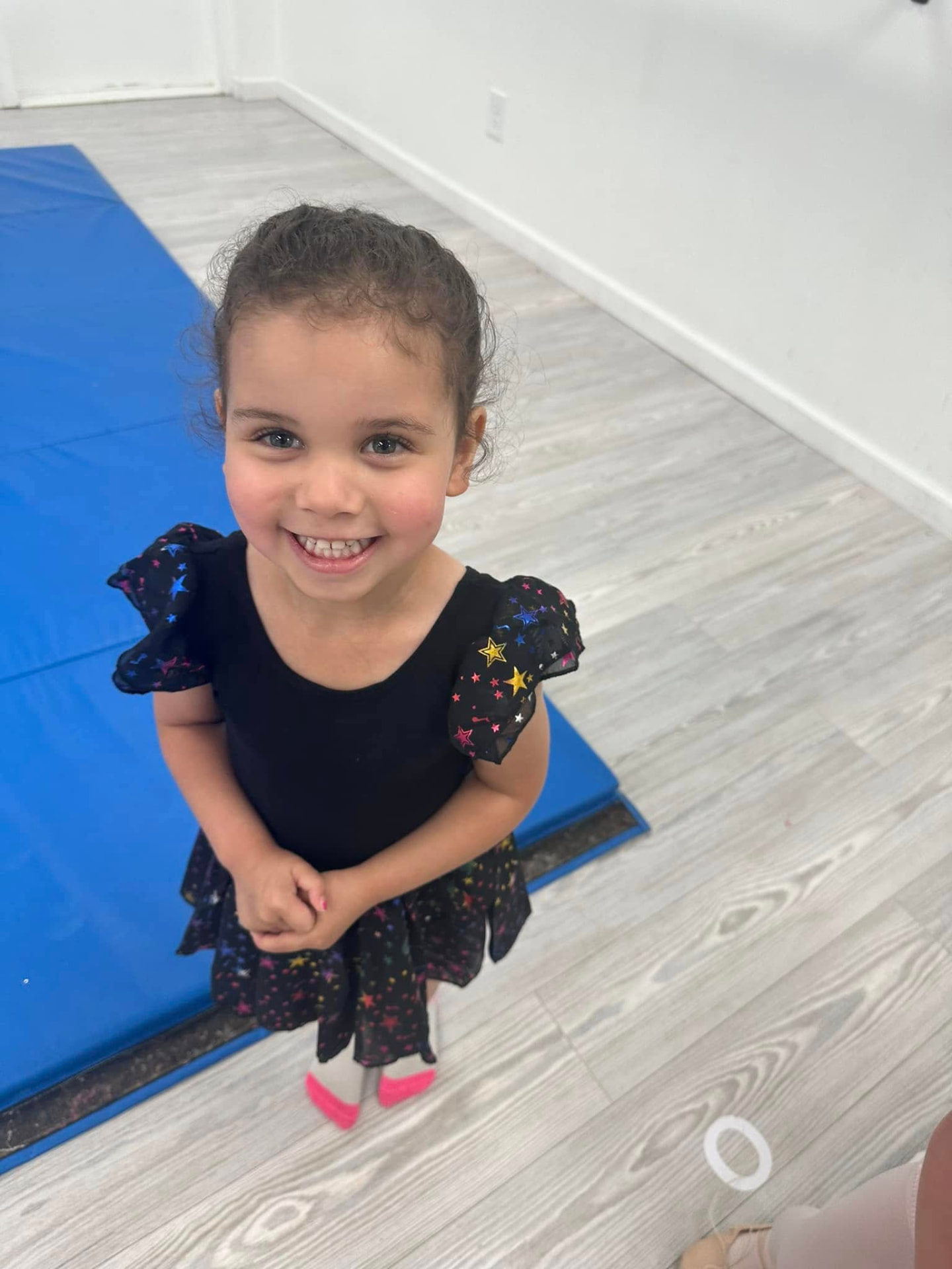 A smiling young dancer in her leotard before class begins